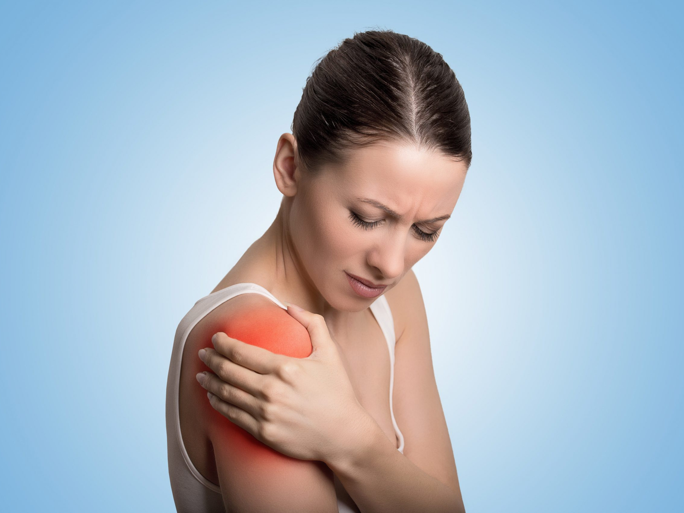 Young woman patient in pain having painful shoulder colored in red. 2 Injured joint. Young woman patient in pain having painful shoulder colored in red. Medicine and health care concept. Blue background